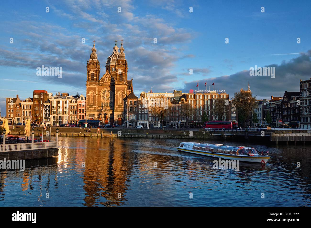 AMSTERDAM, PAESI BASSI - 9 MAGGIO 2017: Barca turistica nel canale di Amsterdam e Chiesa di San Nicola (Sint-Nicolaaskerk) al tramonto. Amsterdam, Olanda Foto Stock