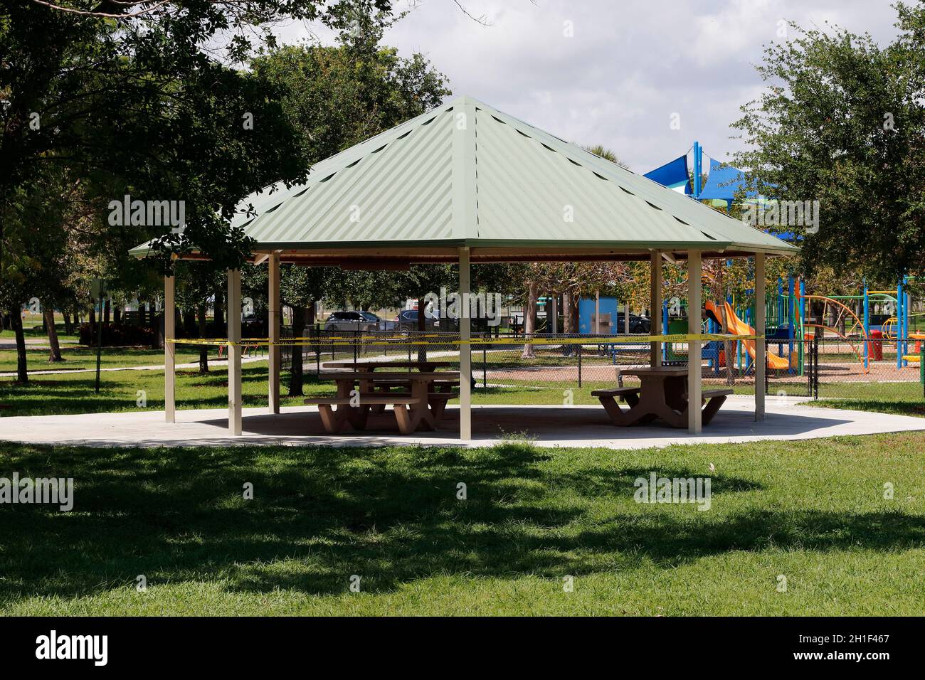 Pompano Beach, FL, USA - 7 aprile 2020: Pompano Beach Park mostrando nastro di avviso intorno ad un padiglione con tavoli da picnic. Con cordoni all'esterno dell'area salotto Foto Stock