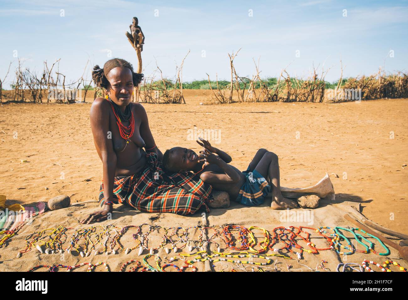 Omorate, Valle dell'Omo, Etiopia - 11 maggio 2019: Donna della tribù africana Dasanesh con bambino che offre souvenir fatti a mano. Daasanach sono etnie Cushitiche Foto Stock