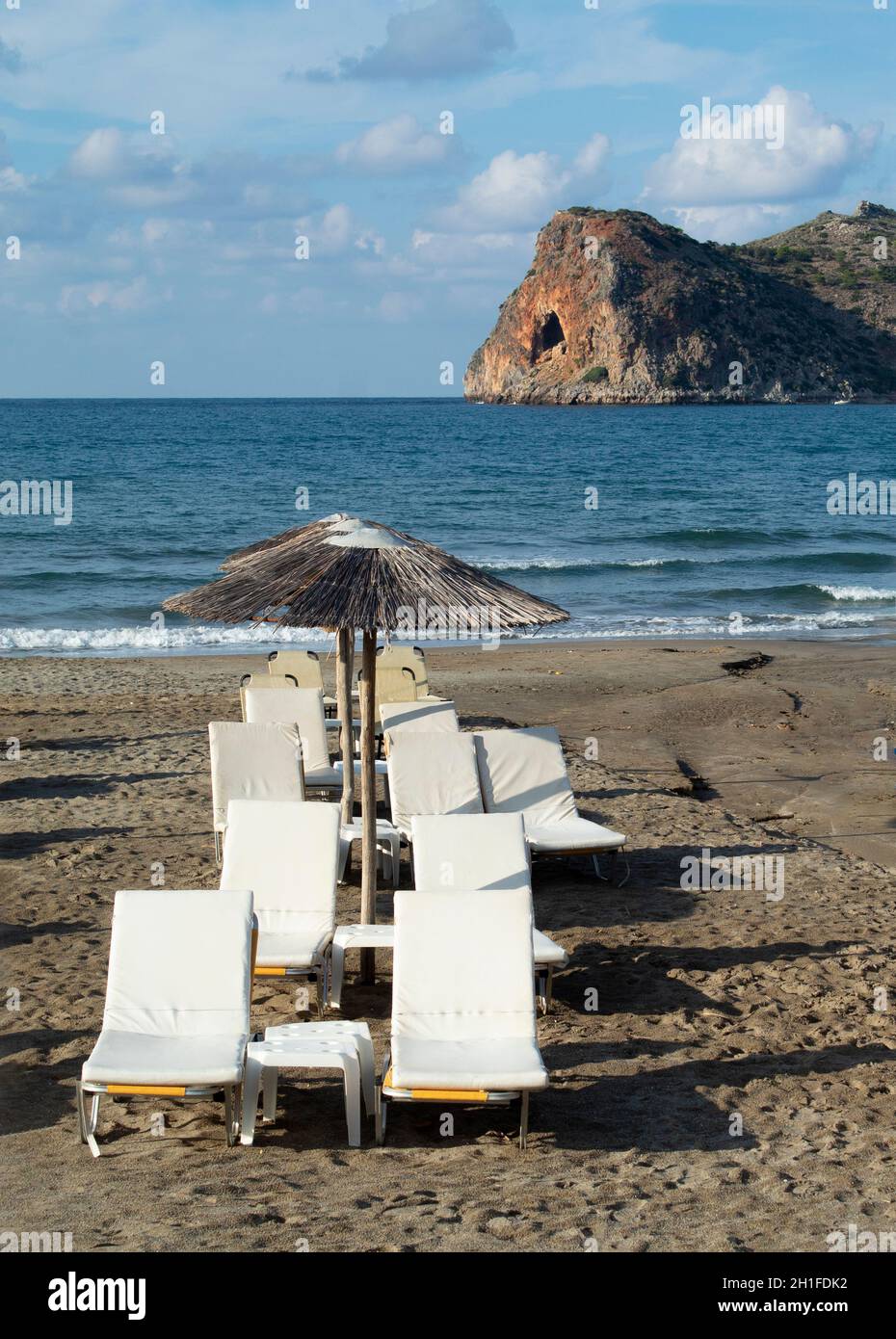 Agia Marina, la Canea Creta splendida spiaggia greca sdraio sulla sabbia verticale colpo con vista isolotto roccioso Foto Stock