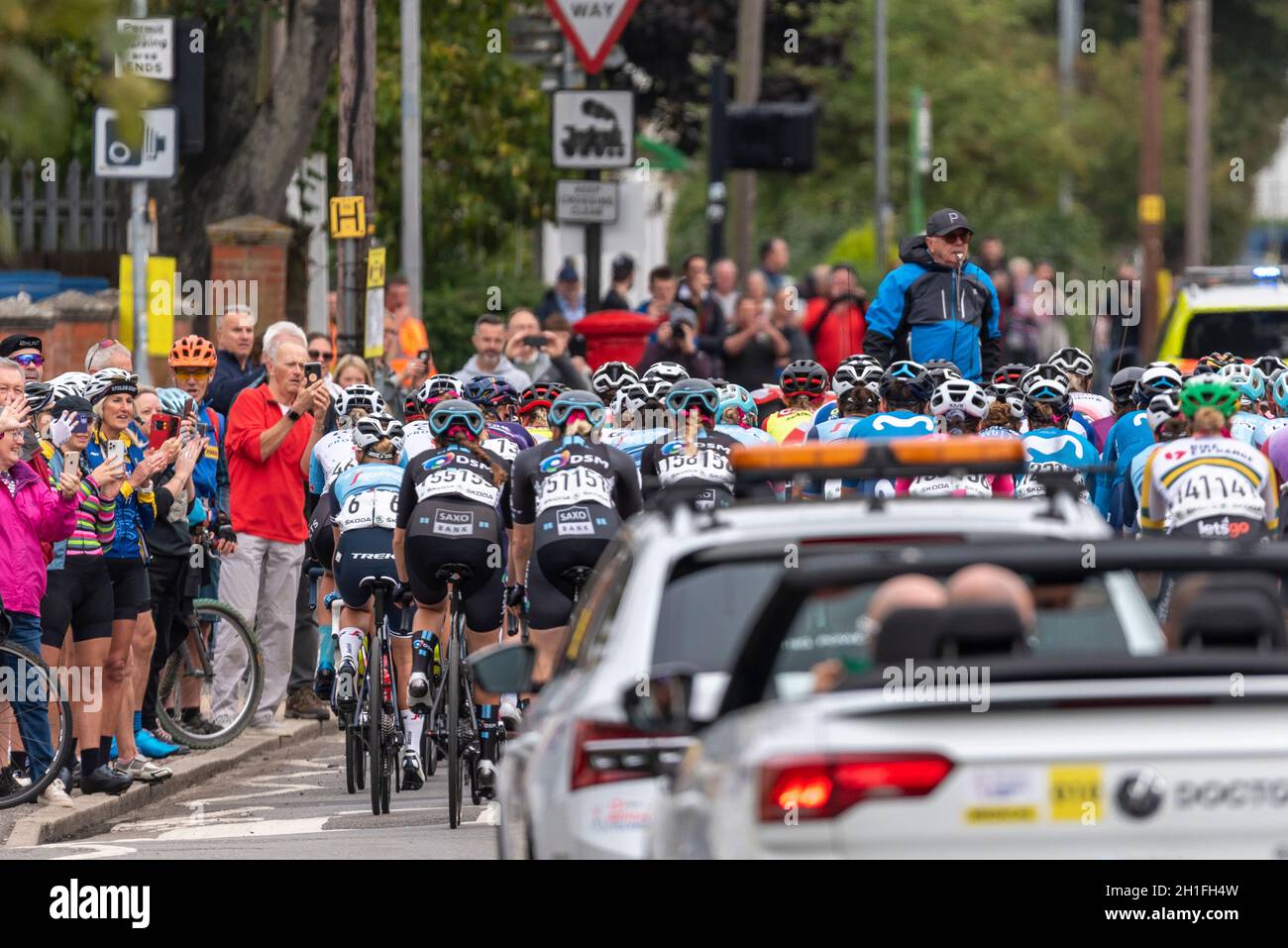 Direttore di gara che guida i piloti attraverso la partenza neutralizzata alla gara ciclistica AJ Bell Women's Tour a Shoeburyness, Essex, Regno Unito. Seguono le auto di supporto Foto Stock