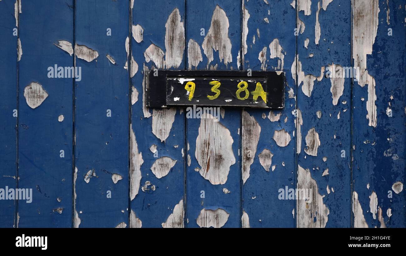 Peeling vernice su una vecchia porta, con crudo mano pittura numeri casa sulla cassetta delle lettere. Decadimento urbano, paesaggio urbano, texture. Foto Stock