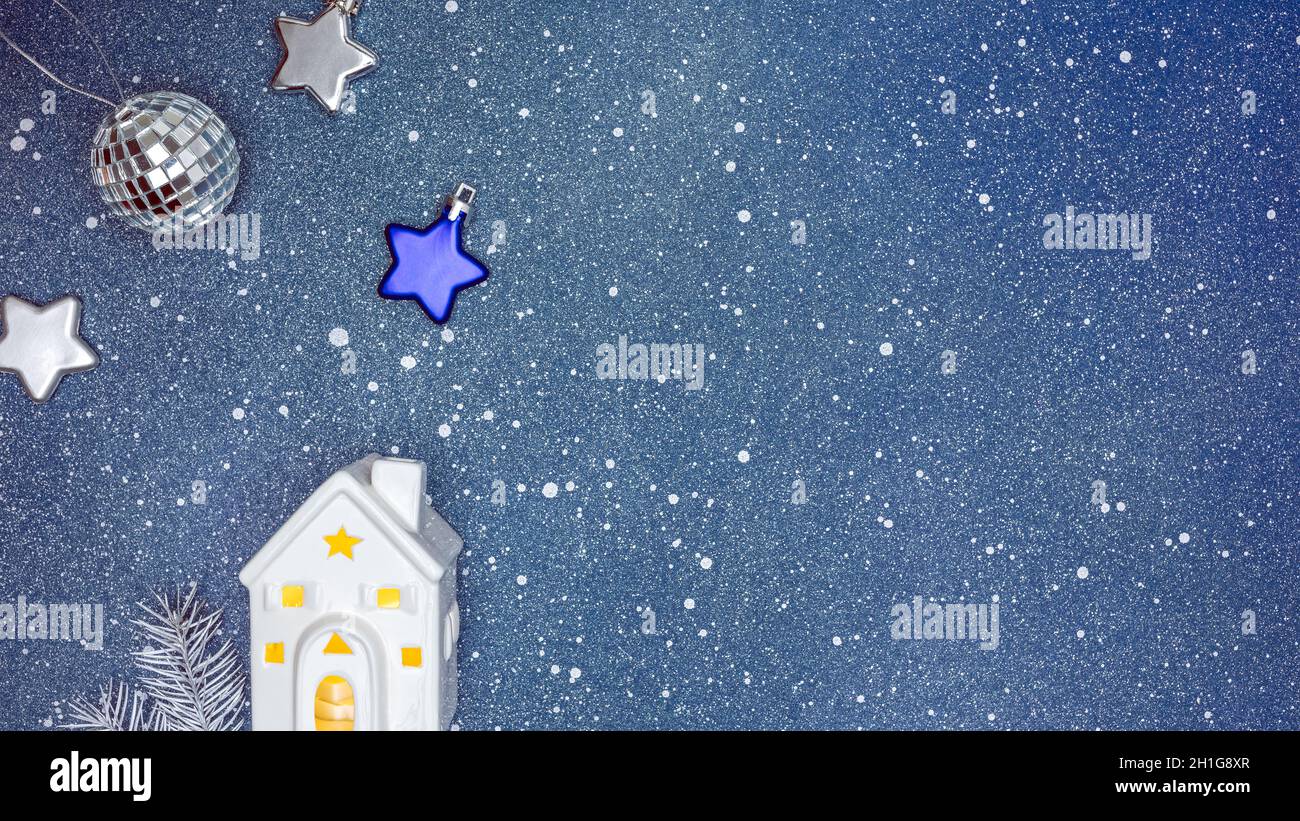 decorazioni natalizie su sfondo blu. casa giocattolo illuminata, palla d'argento e stelle. Foto Stock