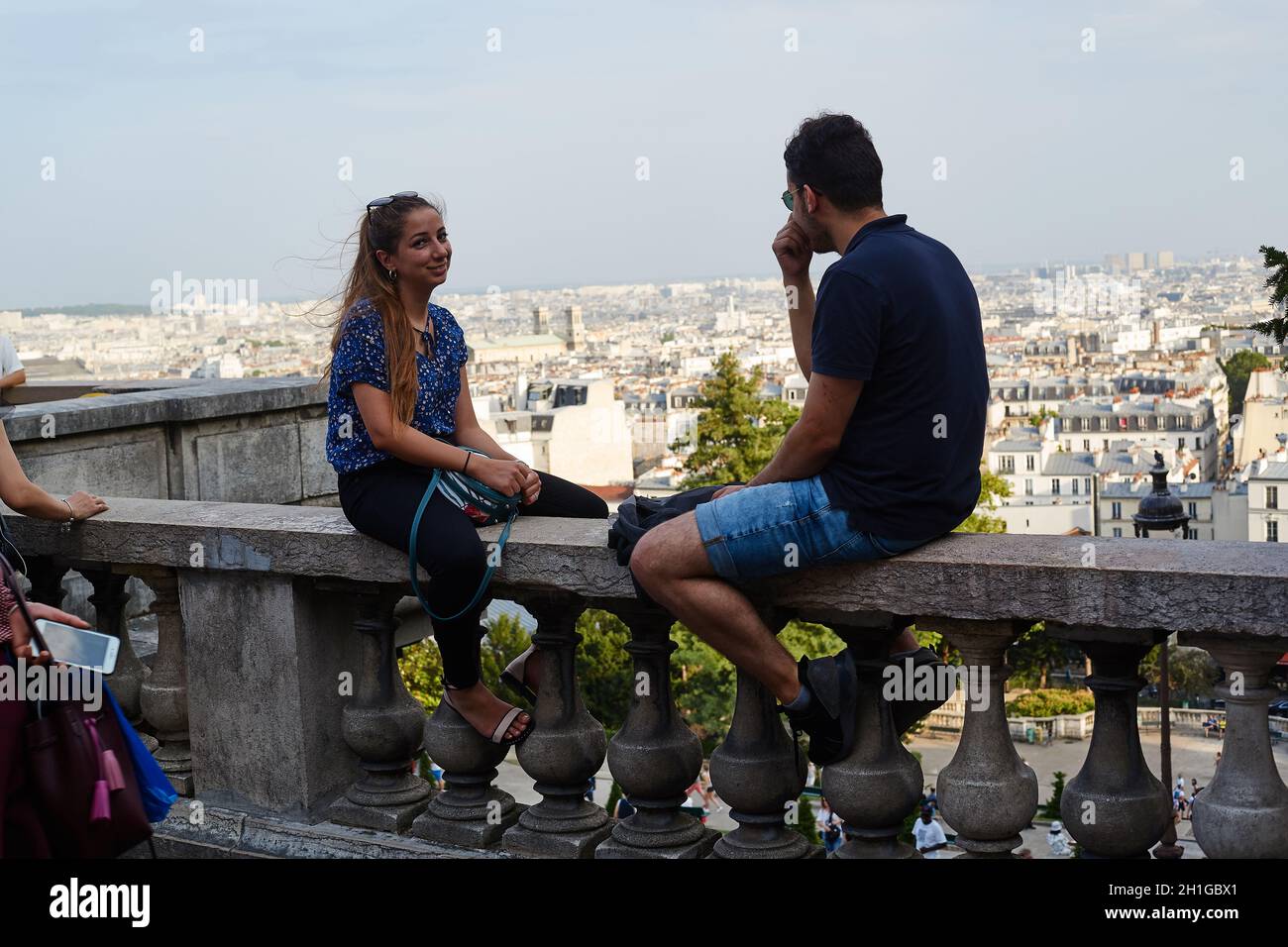 Parigi, Francia - Luglio 2019: Giovane coppia francese seduta sul parapetto al punto di vista di Parigi, situato proprio sotto le scale della Basilica del Sacro Foto Stock