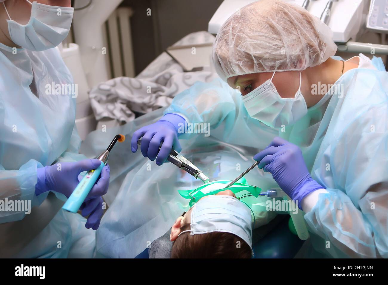 Un chirurgo dentale pediatrico tratta i denti di un ragazzo sotto anestesia generale. Chirurgia dentale. Concetto di salute e prevenzione.Copia spazio. Foto Stock