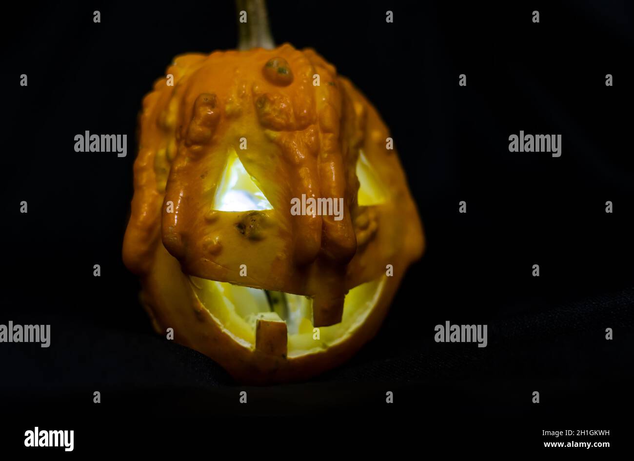 Zucca di Halloween su sfondo nero. Ampia zucca sorridente Jack o Lantern Halloween con luce interna. Zucca scolpita spaventosa. Foto Stock