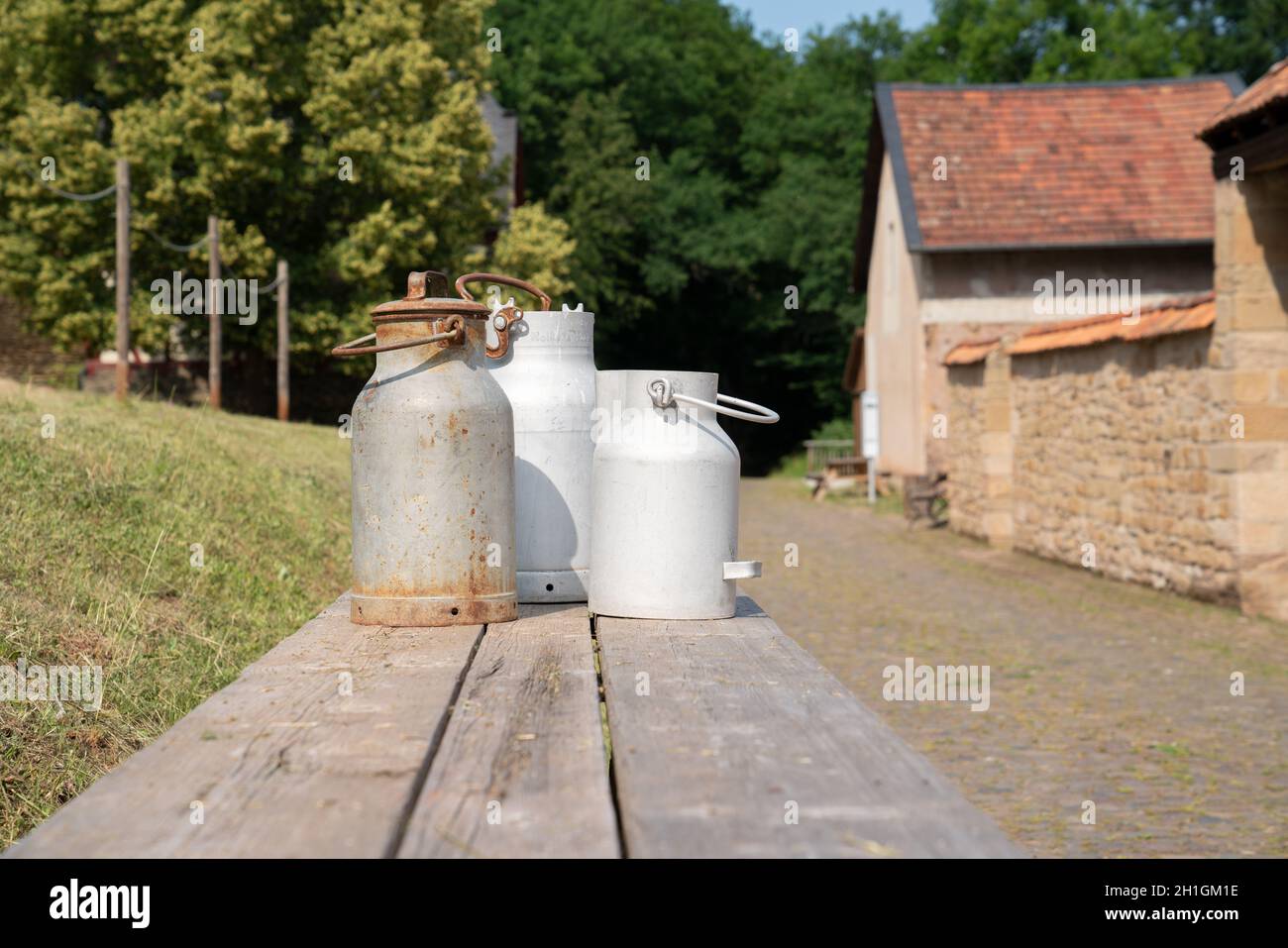 BAD SOBERNHEIM, GERMANIA - 26 GIUGNO 2020: Vecchi churns di latte su una panchina, villaggio museo all'aperto a Bad Sobernheim il 26 giugno 2020 in Germania Foto Stock