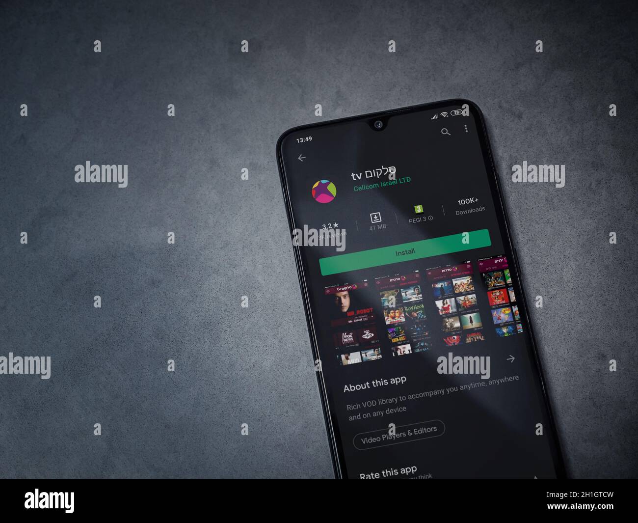 LOD, Israele - 8 luglio 2020: L'app di Cellcom TV gioca la pagina del negozio sul display di uno smartphone nero su sfondo di pietra di marmo scuro. Vista dall'alto piatta Foto Stock