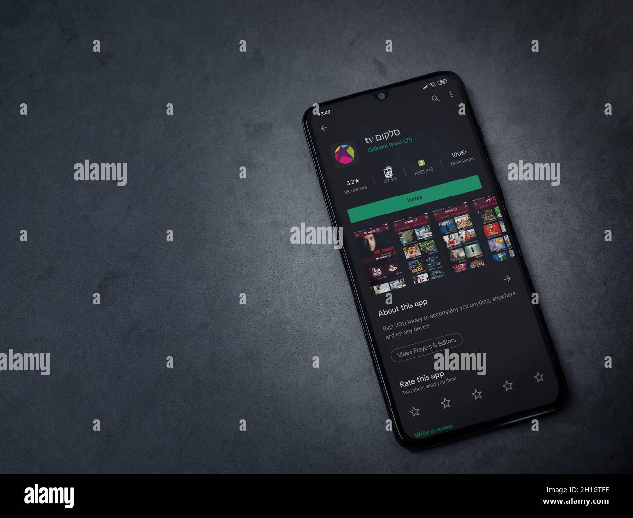 LOD, Israele - 8 luglio 2020: L'app di Cellcom TV gioca la pagina del negozio sul display di uno smartphone nero su sfondo di pietra di marmo scuro. Vista dall'alto piatta Foto Stock
