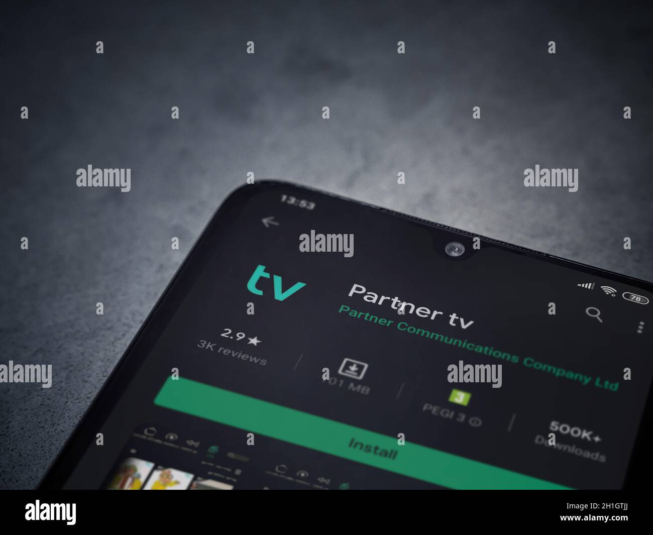 LOD, Israele - 8 luglio 2020: App partner tv play store page sul display di uno smartphone nero su sfondo di marmo scuro in pietra. Vista dall'alto piatta Foto Stock