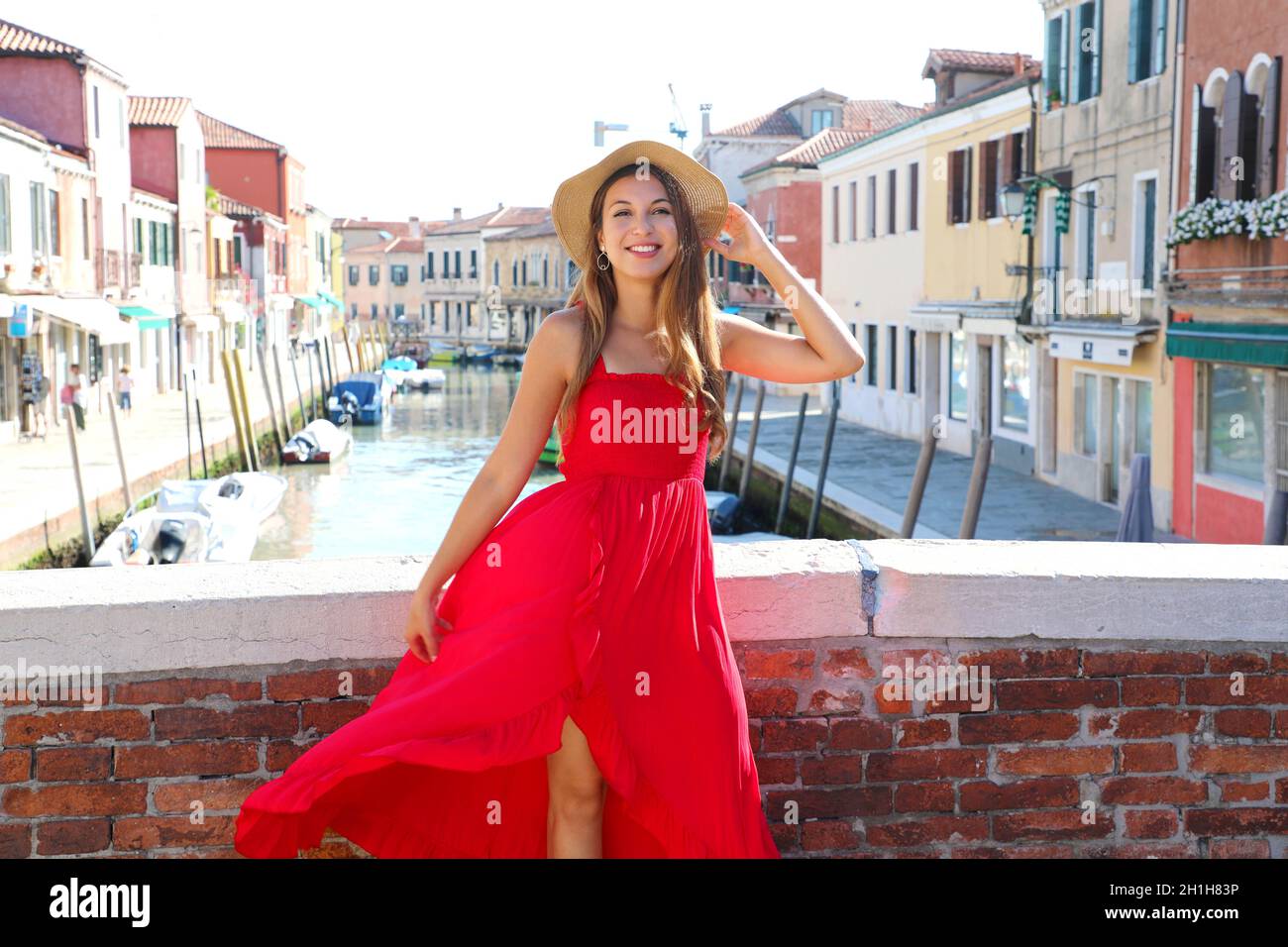 Elegante donna in abito rosso lungo che cammina sul ponte nel centro  storico di Murano, Venezia, Italia Foto stock - Alamy