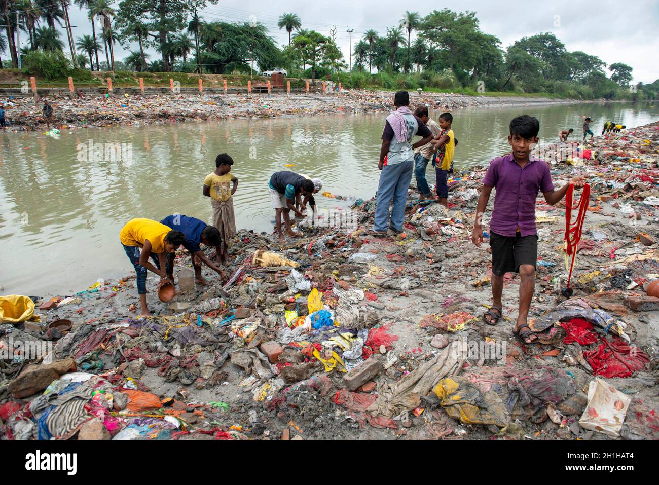 Muradnagar, India. 18 Ott 2021. I locali insieme ai loro bambini setacciano oggetti di valore dalle mucche sulle rive del canale di Gange a Muradnagar. Gli abitanti locali cercano felicemente gli articoli importanti nel canale superiore di Ganges che è accatastato dai torrenti pesanti alle rive del canale. I devoti mentre prendono un tuffo nel canale di Ganga offrono gli oggetti di valore come pratica religiosa o lo perdono inconsapevolmente sopra là. (Foto di Pradeep Gaur/SOPA Images/Sipa USA) Credit: Sipa USA/Alamy Live News Foto Stock