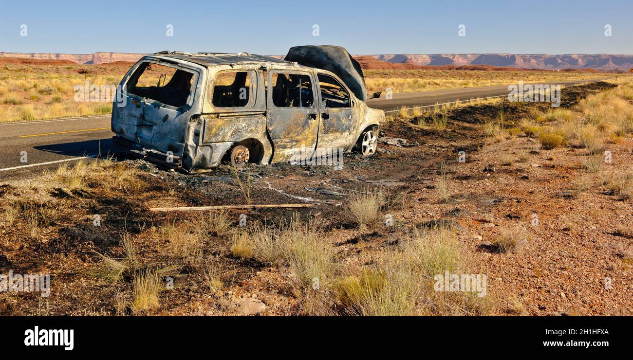 Il guscio bruciato di un veicolo lungo l'autostrada US 163 appena a nord del cappello messicano in Utah. Questa strada conduce alla Valle degli dei. Nessuno è stato ferito d Foto Stock