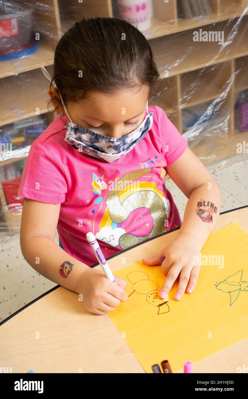 Istruzione Preschool 3-4 anni arte attività ragazza disegno snowman figura con pennarello, tenendo con impugnatura treppiede, indossare maschera Foto Stock