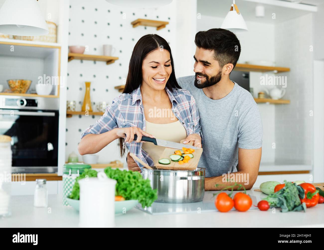 giovane coppia cucina casa di cottura amore felice insieme preparazione ingrediente divertente cibo Foto Stock