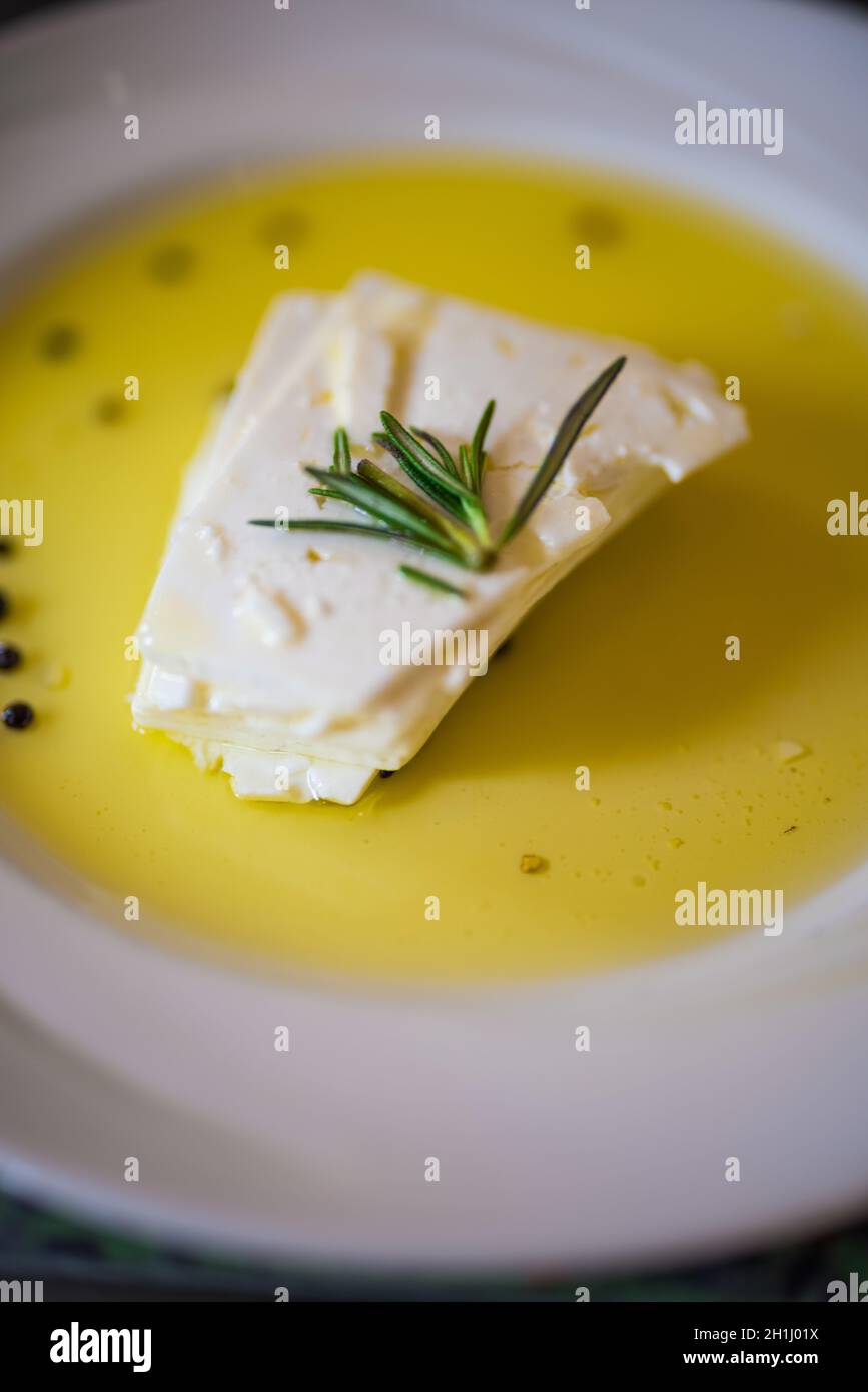 Formaggio di capra servito in olio d'oliva e miele fresco guarnito con Ppercorn e Rosemary Foto Stock