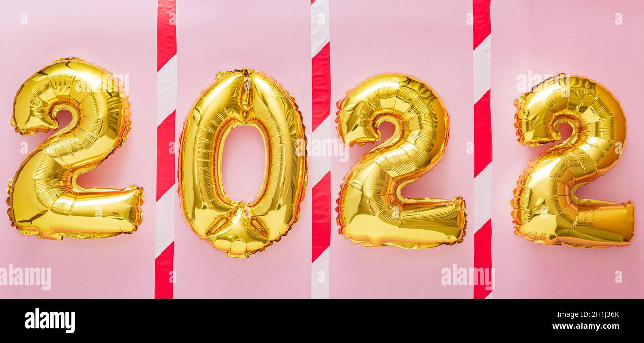 2022 palloncini d'oro in linea con nastro di avvertimento su sfondo rosa per mantenere la distanza sociale durante il covid 19 coronavirus blocco. Natale felice nuovo Foto Stock
