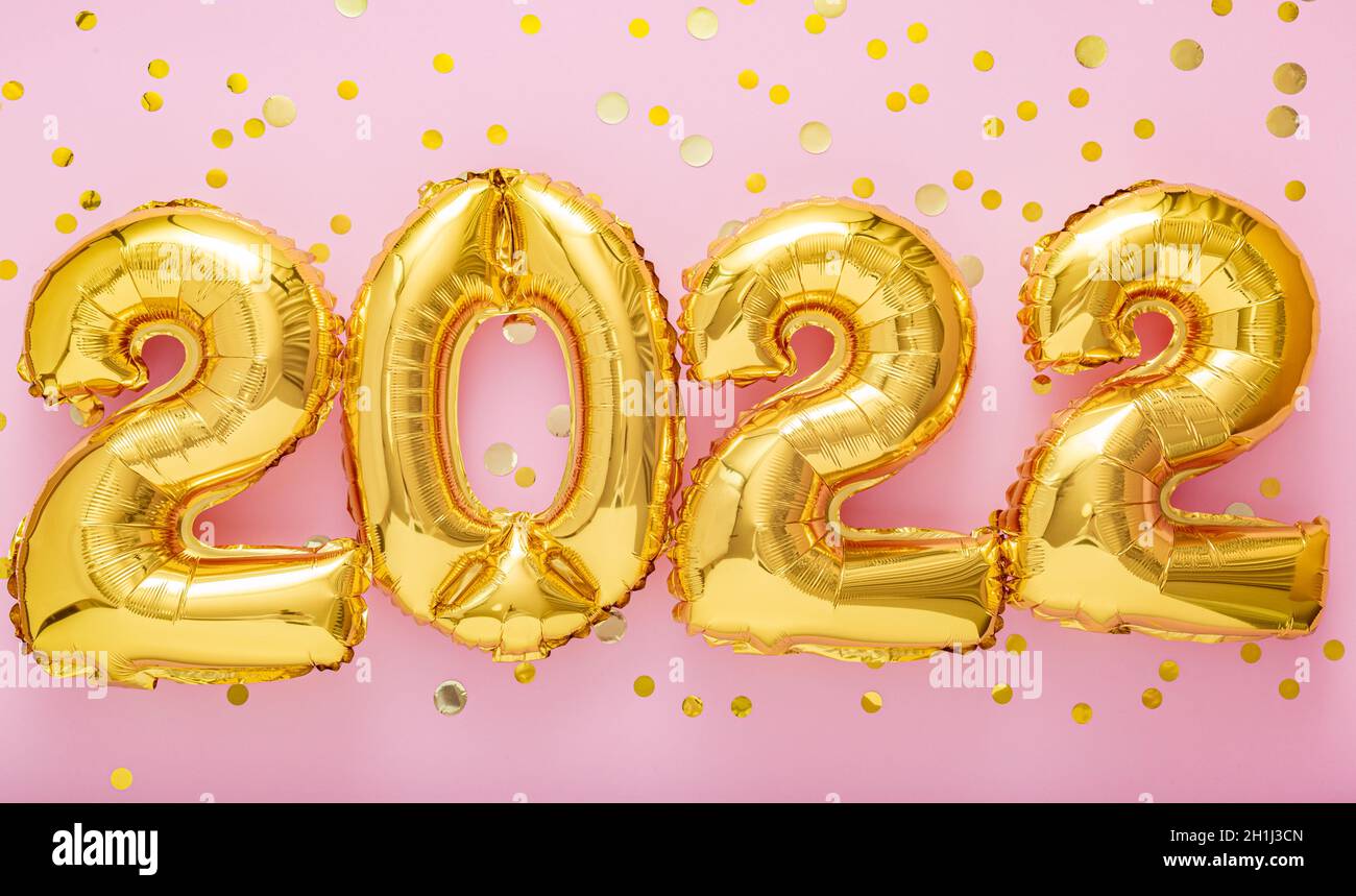 palloncini d'oro a 2022 anni con confetti su sfondo rosa. Felice anno nuovo 2022 lettere festa della vigilia. Buon concetto di Natale. Nastro lungo Foto Stock