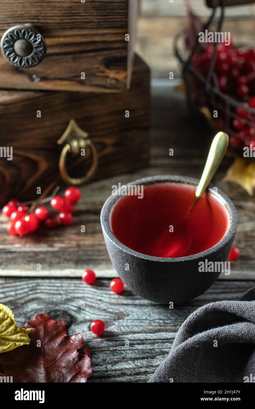 Tè con bacche di viburno in una ciotola , su un tavolo di legno Foto Stock
