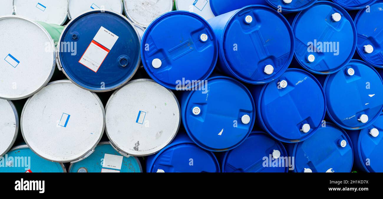 Vecchi barili chimici. Tamburo dell'olio blu e verde. Serbatoio dell'olio in acciaio e plastica. Magazzino dei rifiuti tossici. Cilindro per sostanze chimiche pericolose con etichetta di avvertenza. Industria Foto Stock