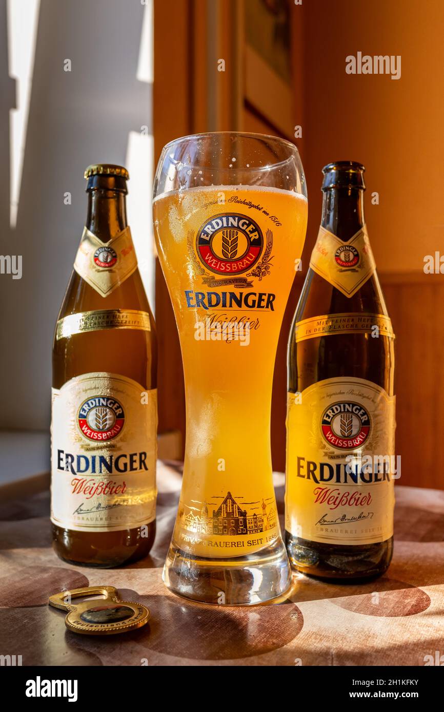 La birra Erdinger viene versata in un bicchiere di birra di marca e. due  bottiglie Foto stock - Alamy