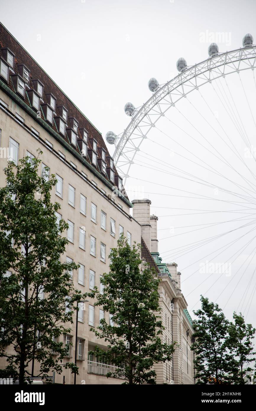 Londra, UK - 4 settembre 2019: Ritratto di un edificio alberghiero con alberi all'esterno e metà dell'Eye of London dietro di esso Foto Stock