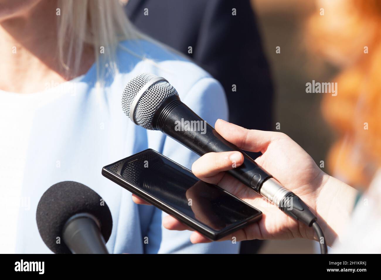 Giornalisti che fanno un'intervista stampa con businesswoman o uomo politico femminile Foto Stock