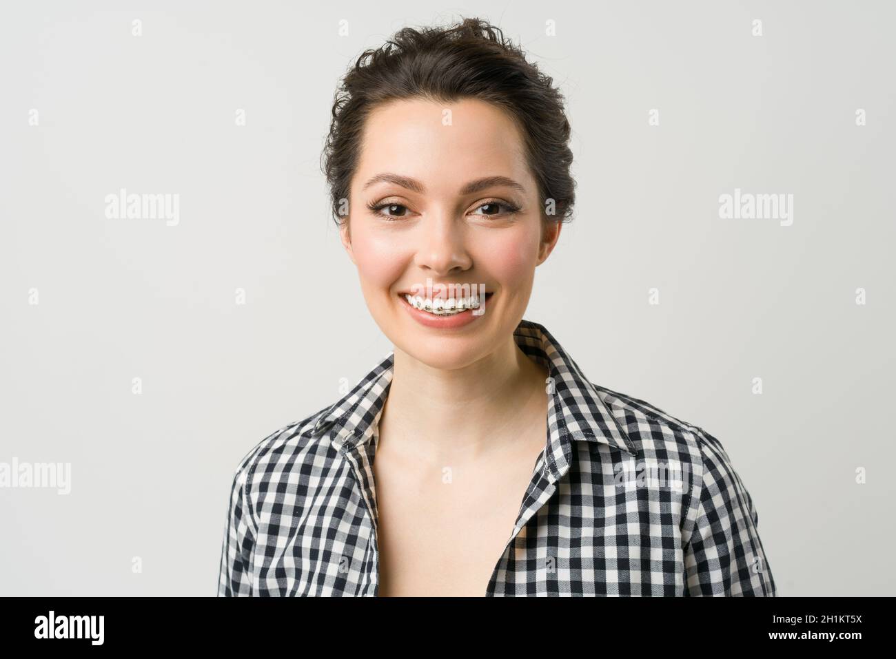 Ritratto di una giovane donna. Una bruna affascinante in una camicia guarda la macchina fotografica e sorride. Foto Stock