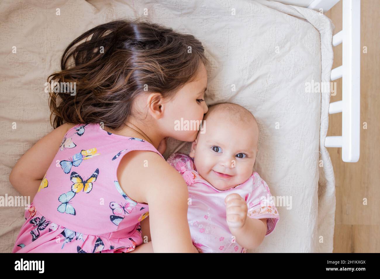 Bambina sdraiata sul letto con amore e pace abbracciando e baciando la  sorella felice del bambino. Sorelle affettive in abbigliamento rosa che  riposano su un letto. Giovane Foto stock - Alamy