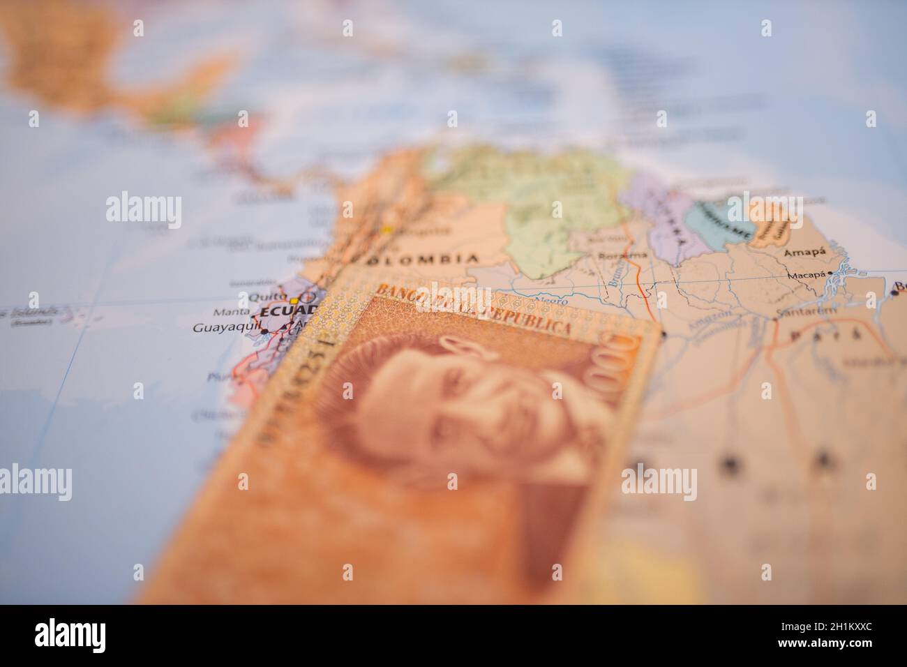 Una banconota da mille pesos colombiani -con le parole Banca della Repubblica in spagnolo- sotto la Colombia su una mappa del Sud America Foto Stock