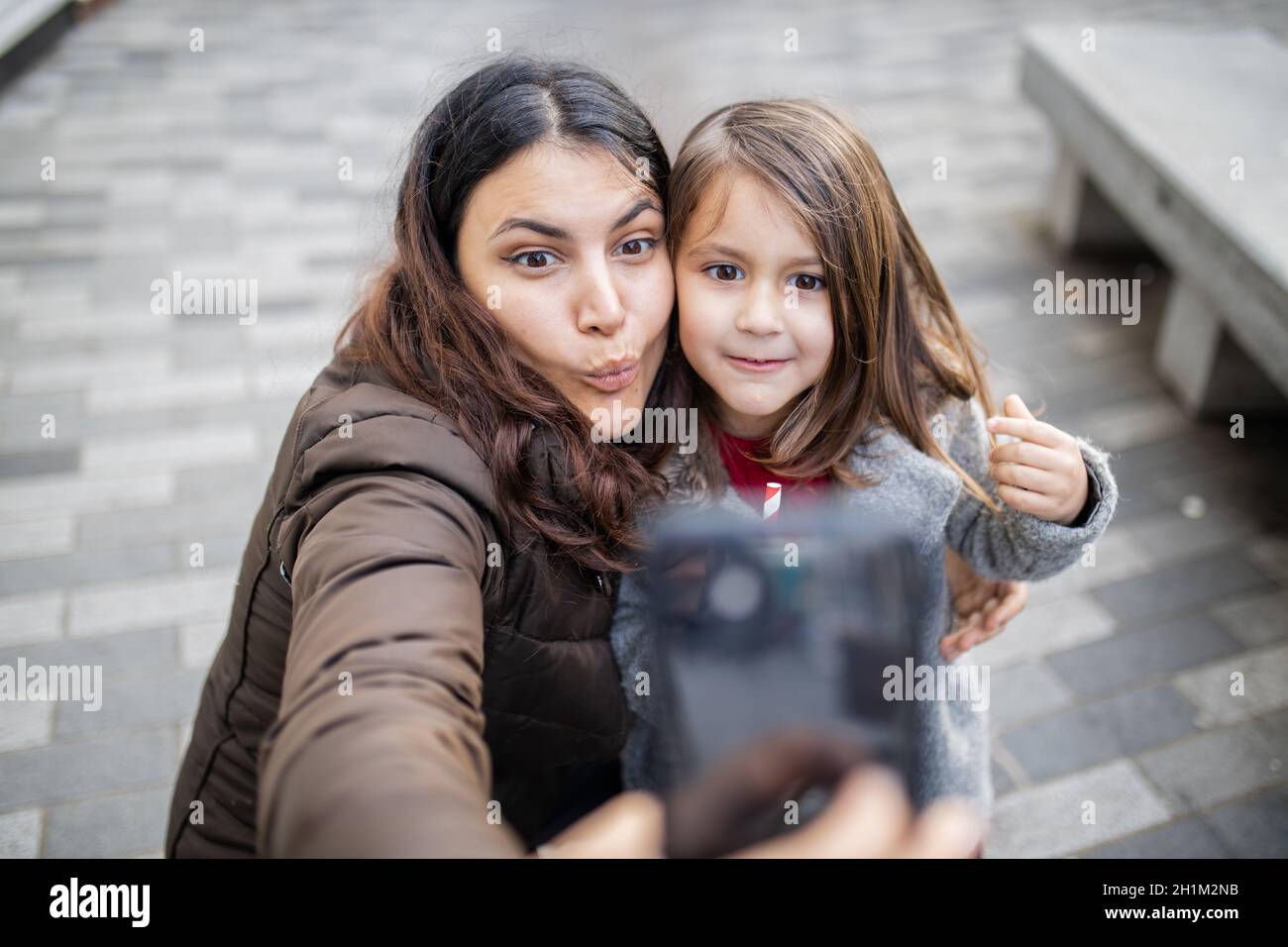 Madre felice e figlia piccola prendere un selfie mentre fa i volti divertenti. Madre-figlia divertirsi a scattare foto. Selfie divertenti Foto Stock