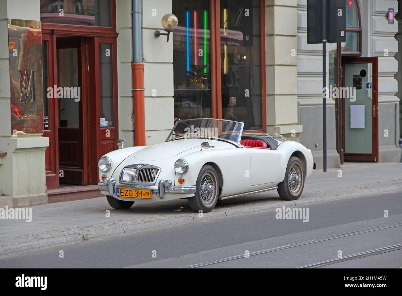MG auto cabriolet sulla strada di Lodz. Auto bianca MG cabriolet in piedi sul marciapiede della strada cittadina a Lodz. Carroadster bianco convertibile MGA da 1960 MG parcheggiato su ci Foto Stock