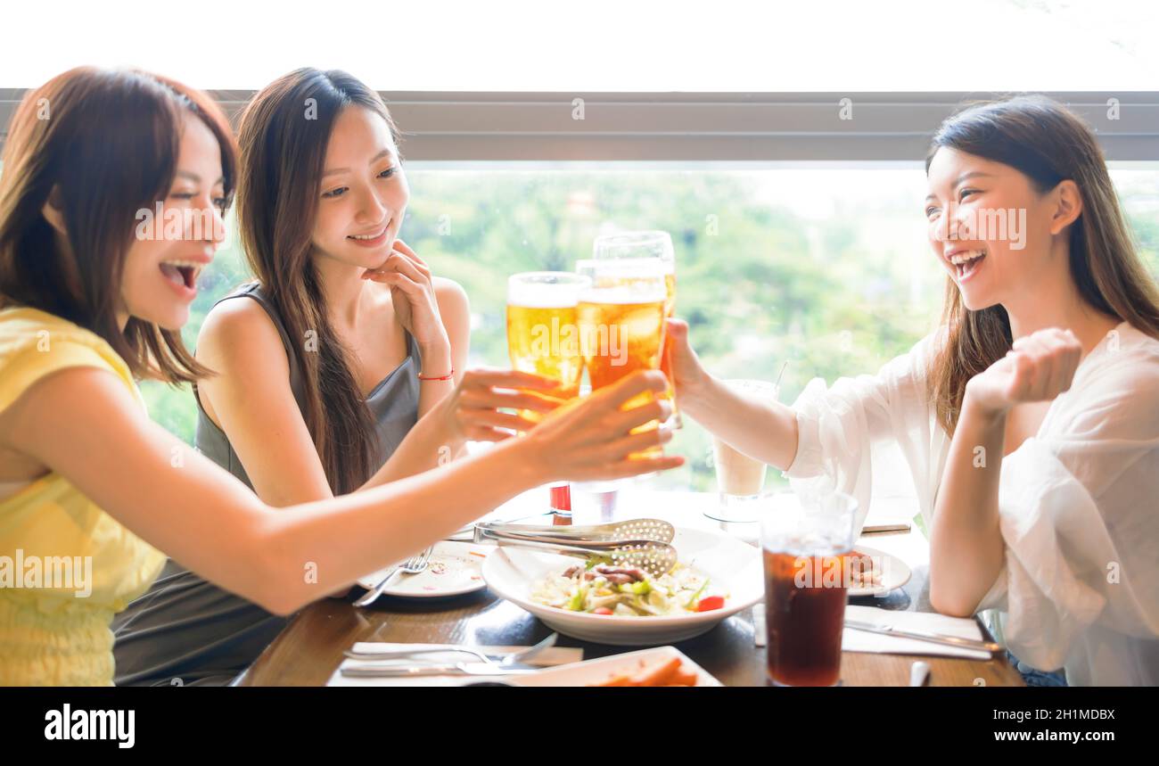 Felice giovane donna amici che si aggraffano bicchieri di birra nel ristorante Foto Stock