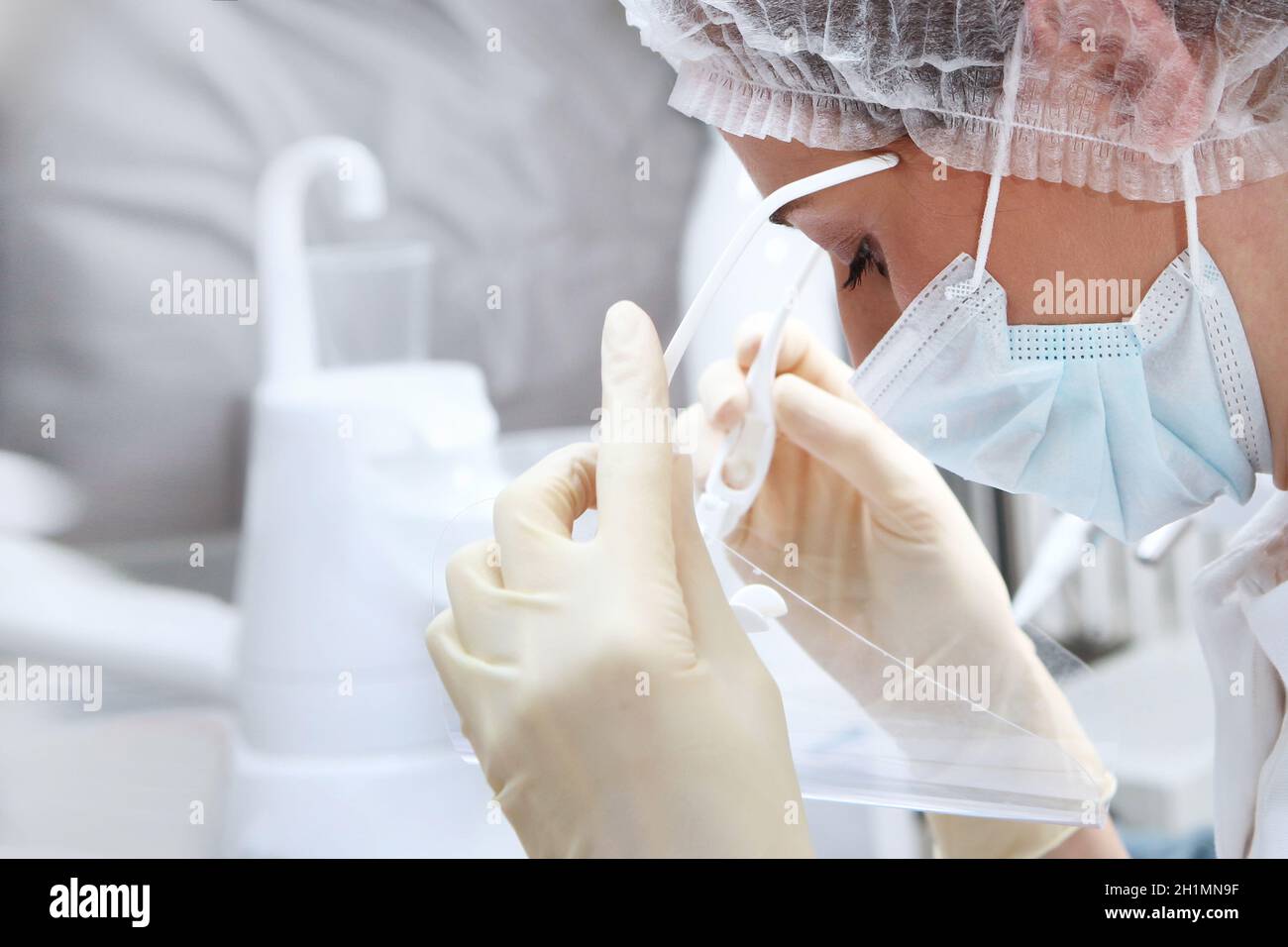 Il medico mette uno schermo protettivo sul suo viso. Indossare guanti protettivi. Il concetto di salute. Prevenzione delle malattie. Spazio di copia. Foto Stock
