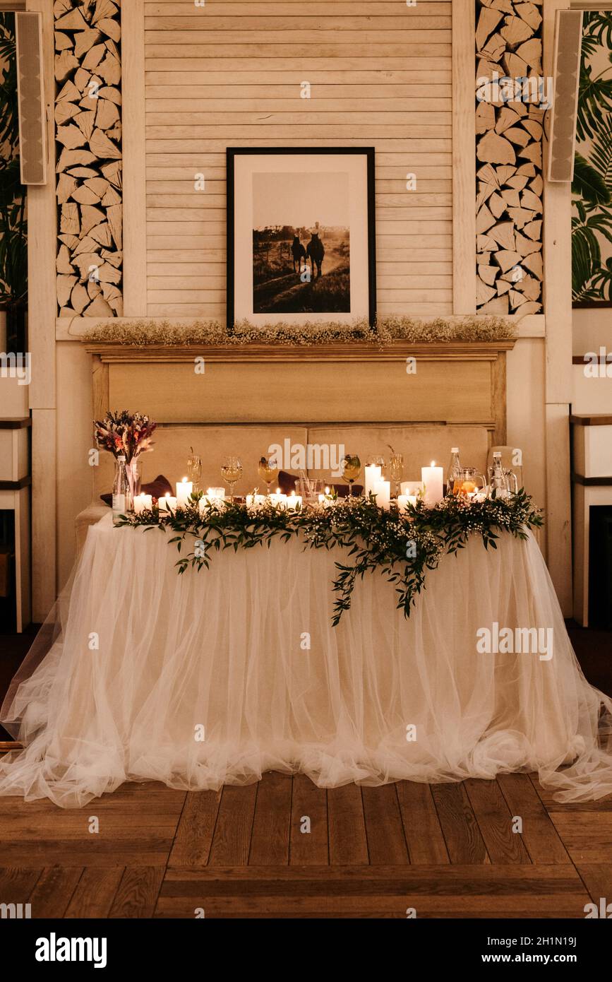 il presidio degli sposi novelli nella sala banchetti del ristorante è decorato con candele e piante verdi, il tono generale della sala è beige Foto Stock