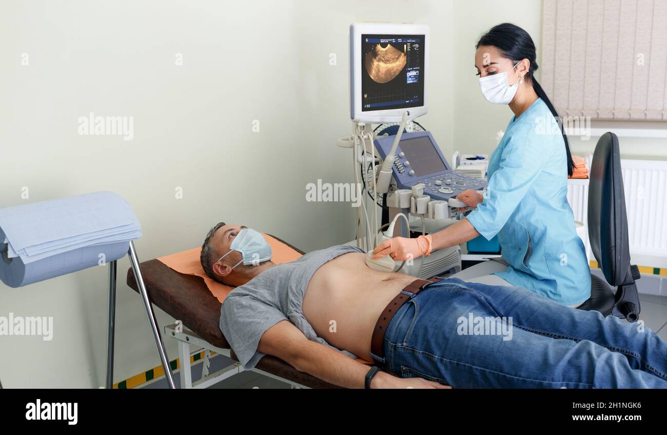 Diagnosi ecografica dello stomaco sulla cavità addominale di un uomo in clinica, vista ravvicinata. Il medico fa funzionare un sensore a ultrasuoni sopra la patie Foto Stock