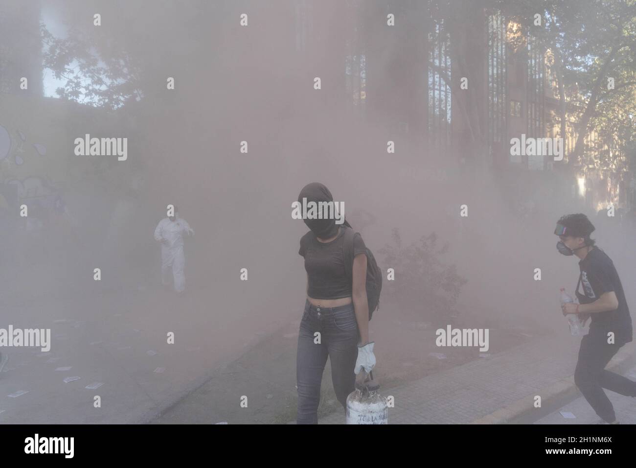 Santiago, Metropolitana, Cile. 18 Ott 2021. Manifestanti sotto il fumo di un estintore, durante una protesta per il secondo anniversario dell'epidemia sociale contro il governo di Sebastian Pinera, a Santiago, Cile, il 18 ottobre 2021. (Credit Image: © Matias Basualdo/ZUMA Press Wire) Foto Stock