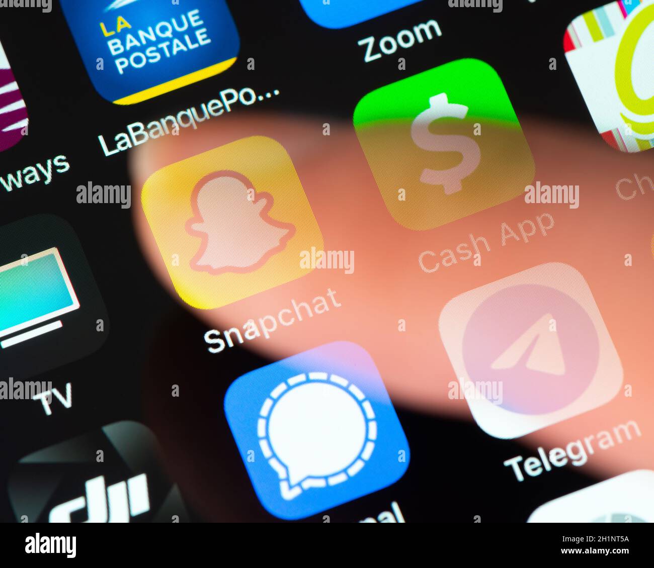 BAYONNE, FRANCIA - CIRCA GENNAIO 2021: Dito semitrasparente toccare l'icona dell'applicazione Snapchat sullo schermo di Apple iPhone. Snapchat è uno sviluppatore di applicazioni di messaggistica multimediale Foto Stock