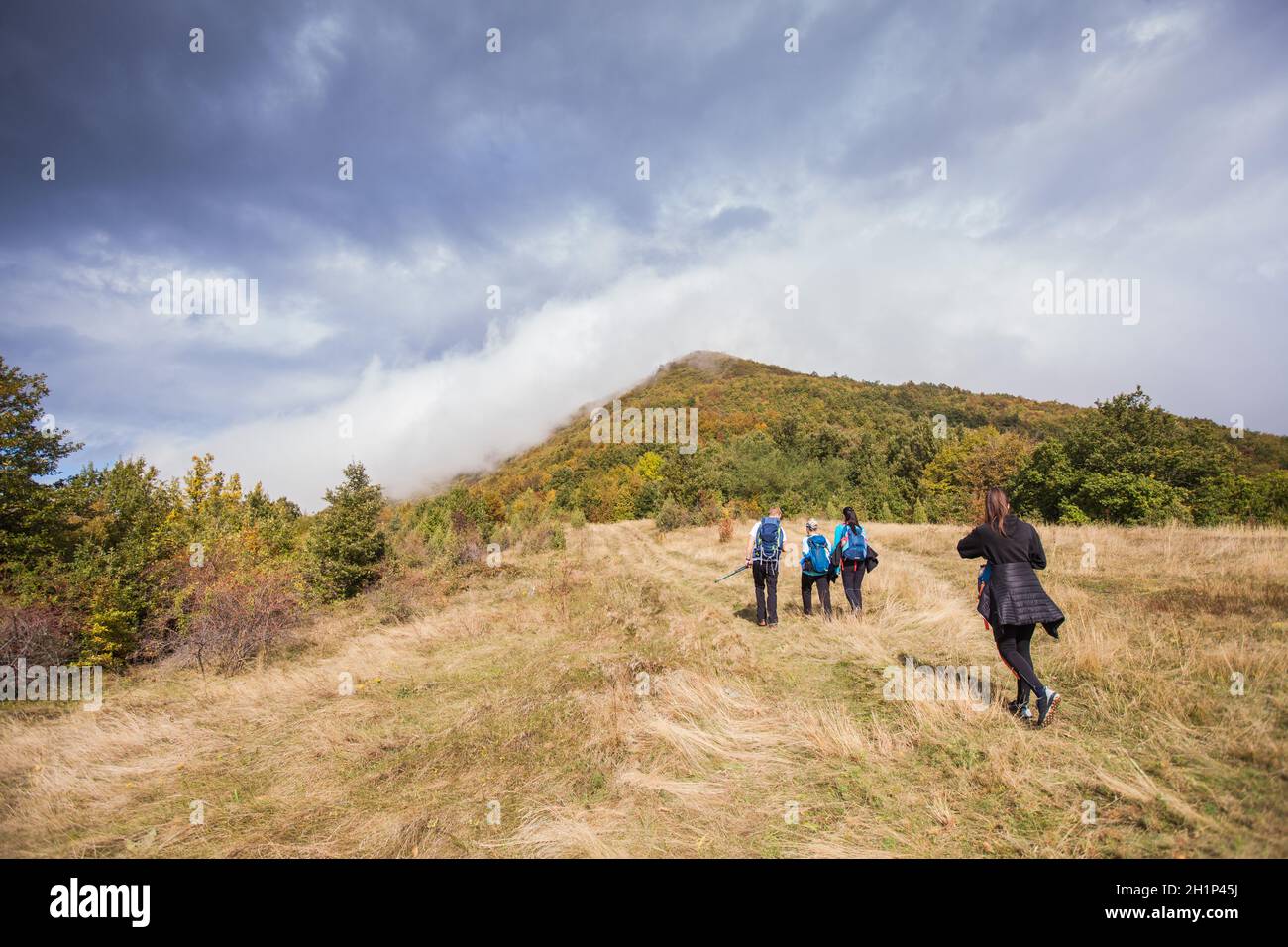 Gruppo di persone attive escursioni in autunno giorno attraverso il bellissimo paesaggio naturale. Misty Mountain Peak. Vista posteriore. Cielo nuvoloso sullo sfondo. Foto Stock