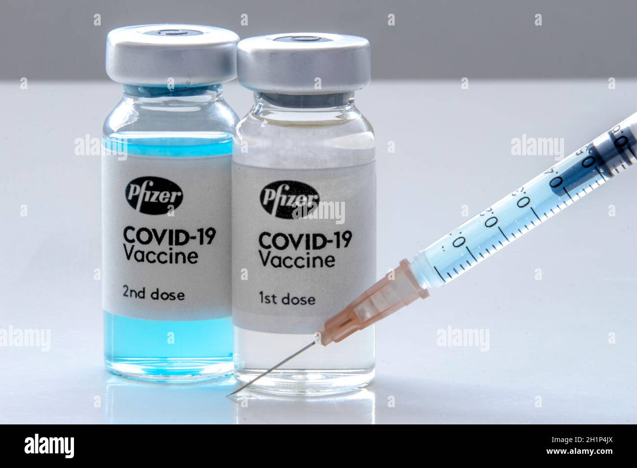 Calgary, Alberta, Canada. 27 novembre 2020. Una prima dose di Pfizer e una seconda dose di vaccino covid-19 su un flacone di flaconcino e siringa per iniezione su una compressa bianca Foto Stock