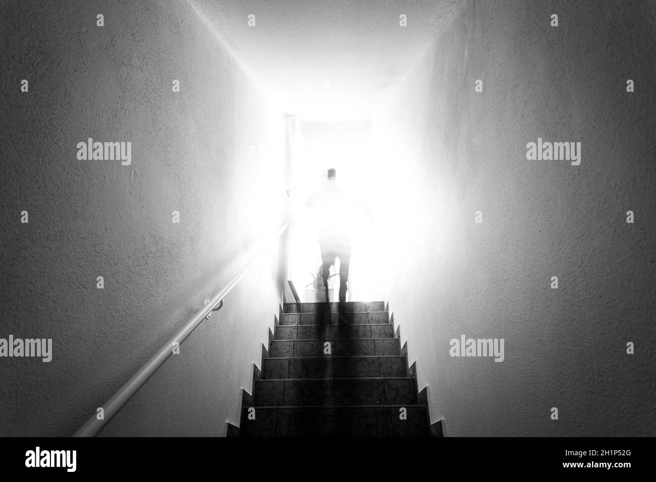 L'uomo sta salendo sulle scale del seminterrato con balaustra. Luce solare naturale e luminosa. Foto Stock