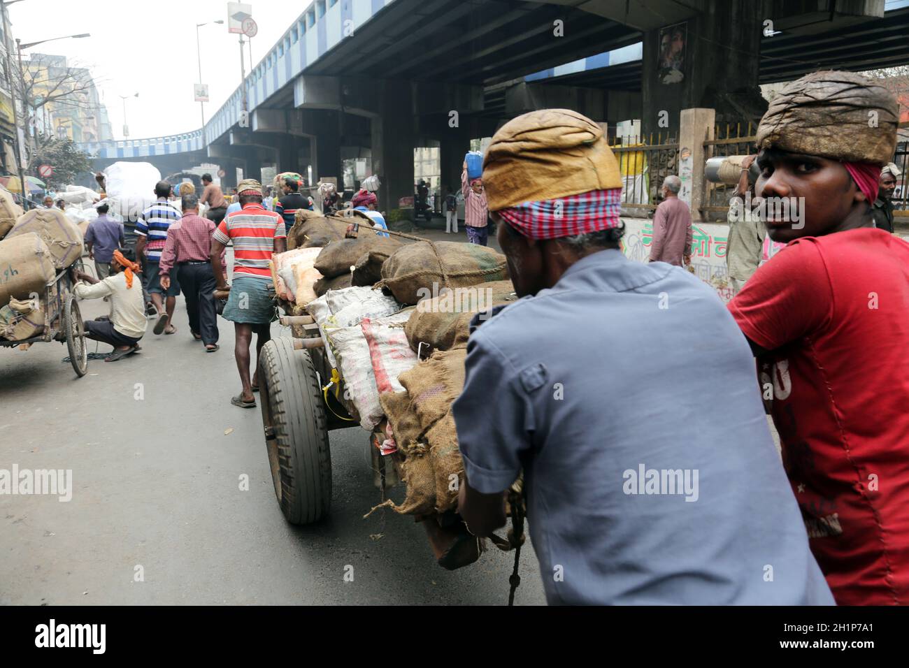 Gli indiani che lavorano duramente spingono carichi pesanti attraverso le strade di Kolkata, India Foto Stock