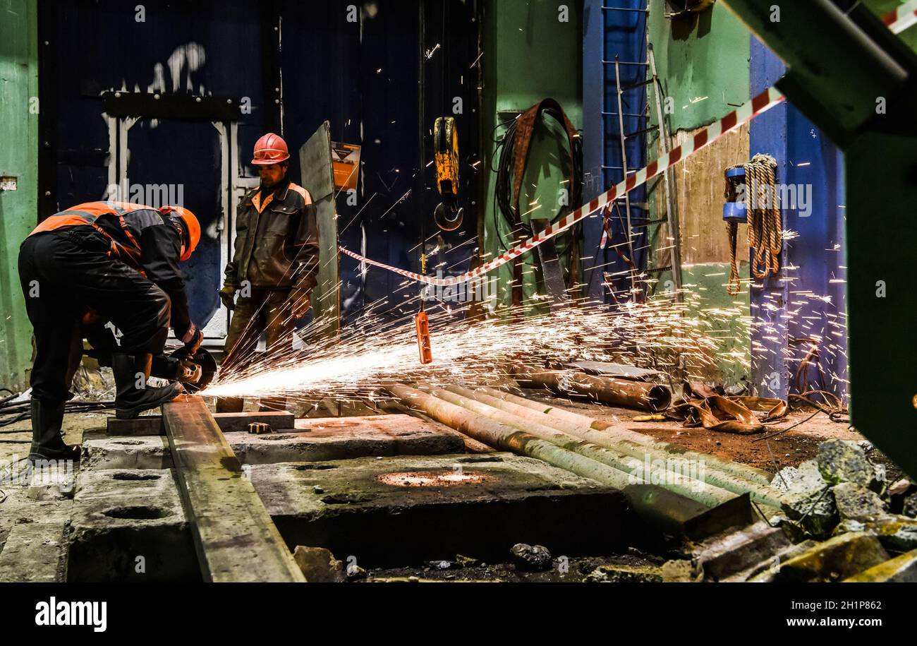 Taglio di metallo con una smerigliatrice angolare. Lavoratori in fabbrica. Foto Stock