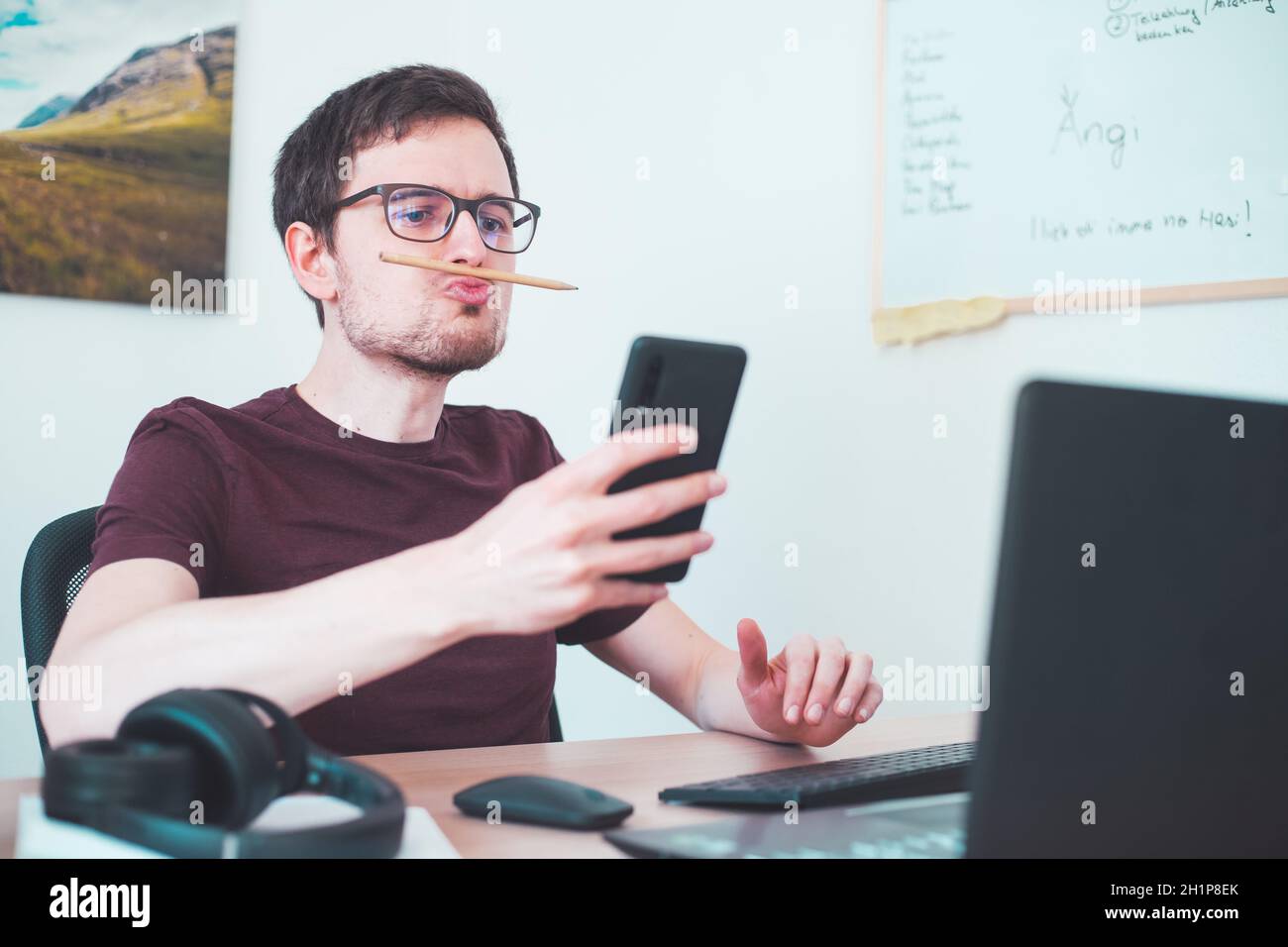 Il freelancer annoiato è ingannato intorno con una matita fra le sue labbra ed il naso Foto Stock