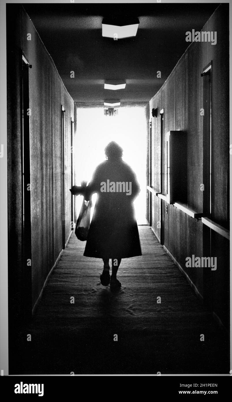 la donna da sola ritorna a casa dallo shopping camminando lungo un corridoio scuro Foto Stock