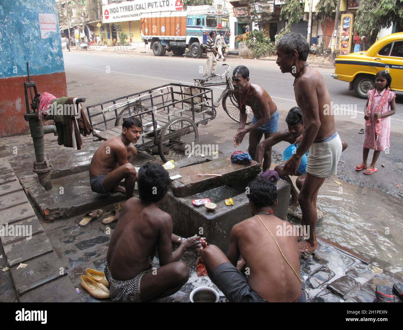 Strade di Kolkata. La gente indiana si lava su una strada. Foto Stock