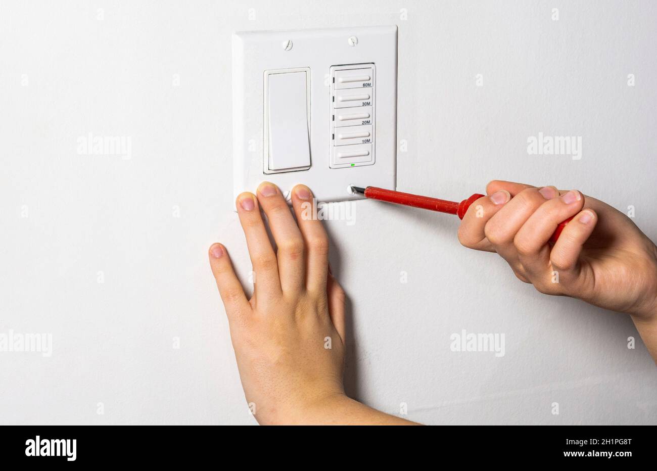 Il tecnico stringe l'ultima vite sul timer della ventola e. interruttore luci Foto Stock