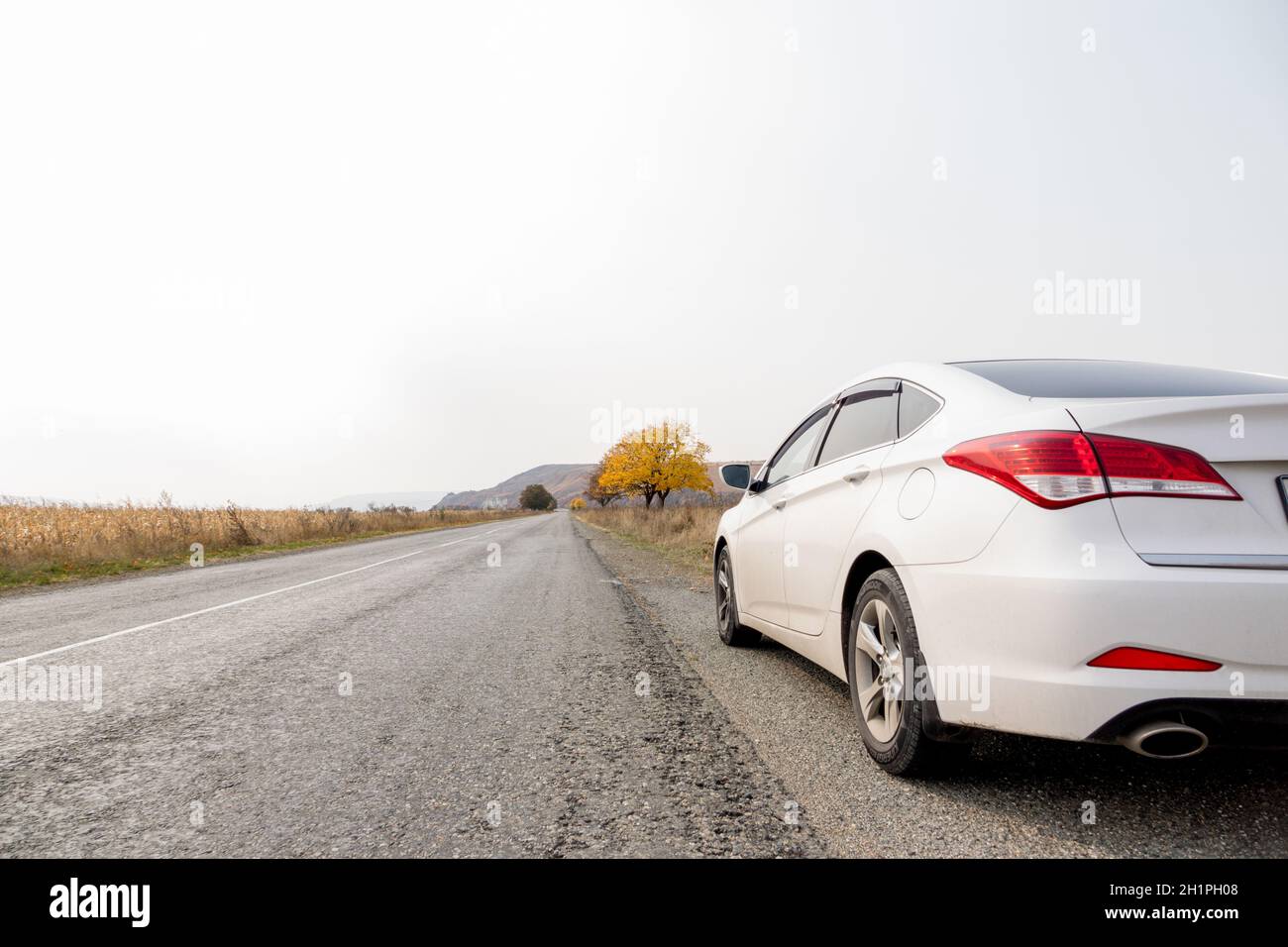 Berlina passeggero bianca sul bordo della strada che si estende a distanza. Gita autunnale in auto alle Highlands. Concetto è viaggi e turismo. Riserva naturale in Foto Stock