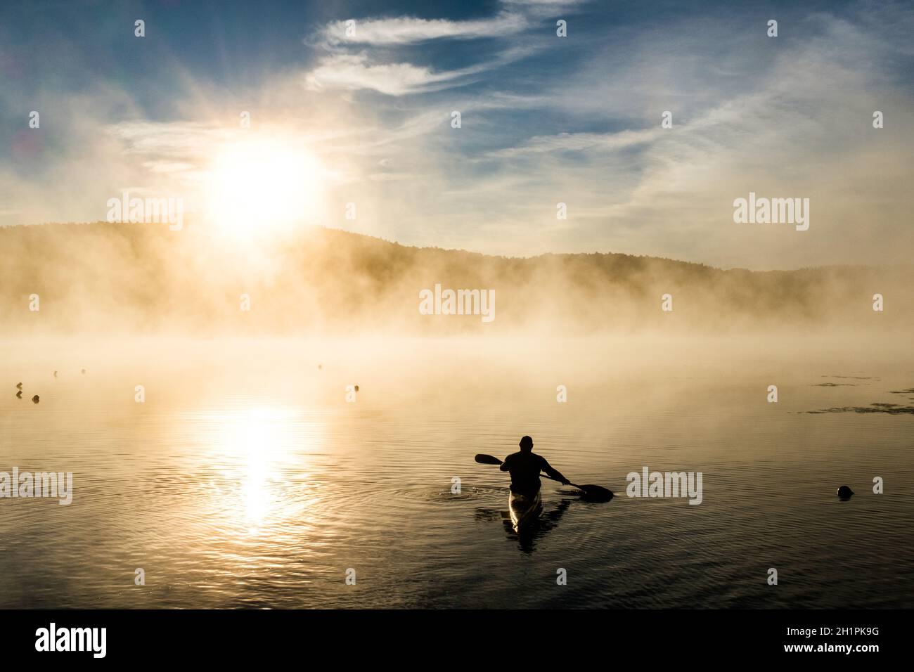 Kayak silhouetted dal sole nascente sul lago Iroquois in Vermont, USA, New England, in una mattinata di settembre nebbiosa. Foto Stock