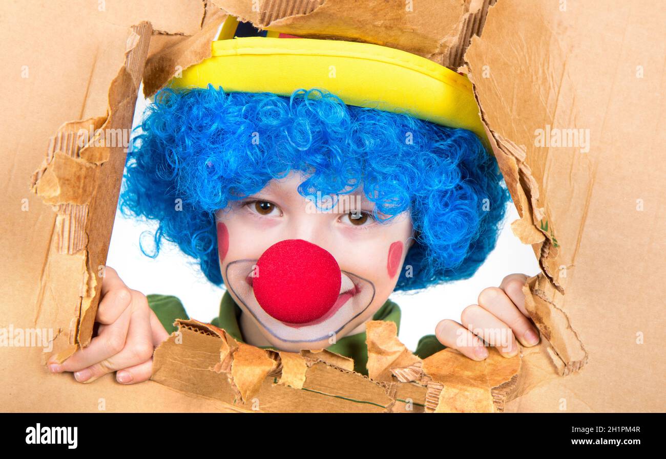 il bambino vestito come un pagliaccio con la parrucca e il naso falso ha  divertimento che guarda dal cartone aperto Foto stock - Alamy
